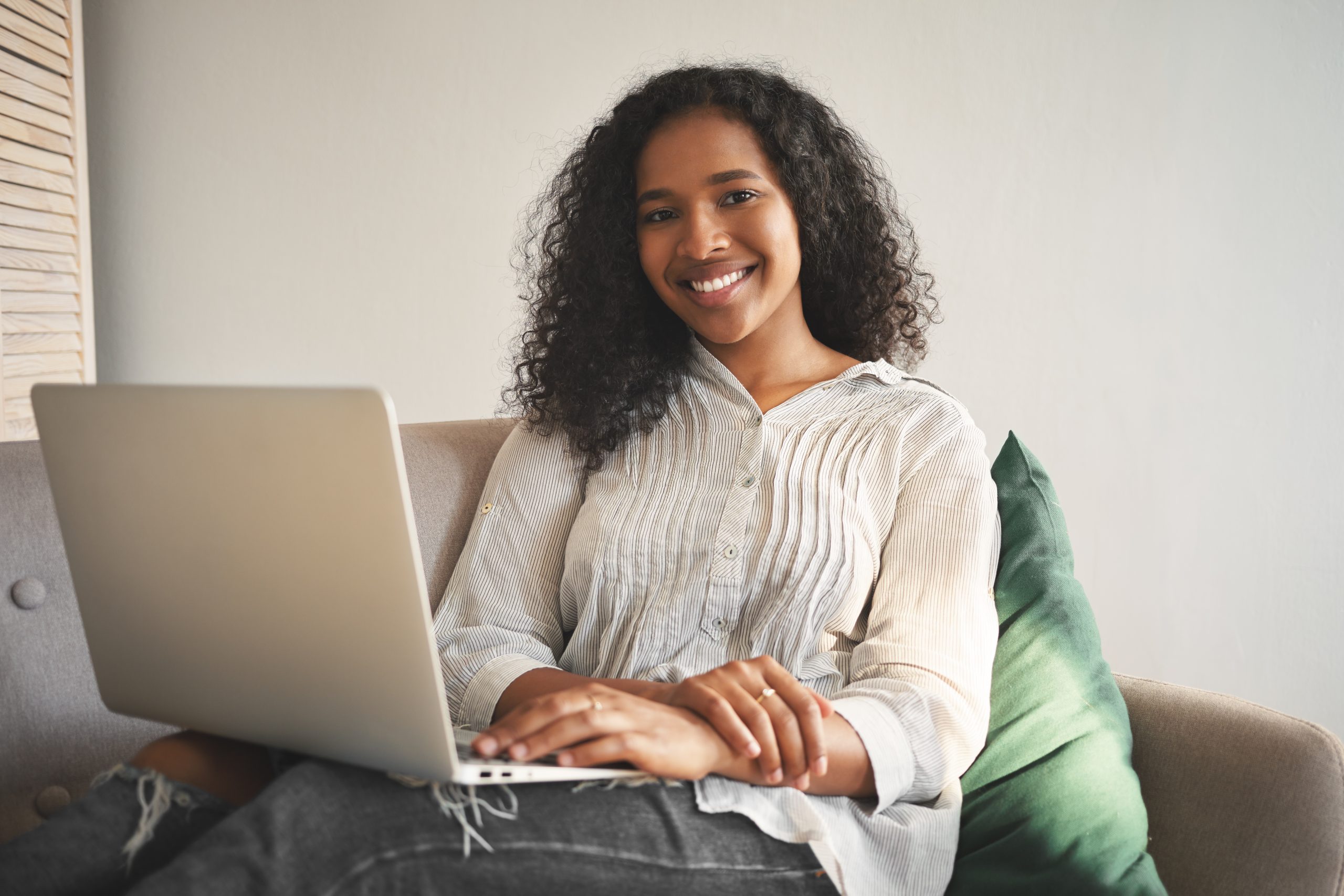 Portrait of cheerful young African woman in jeans and shirt smil